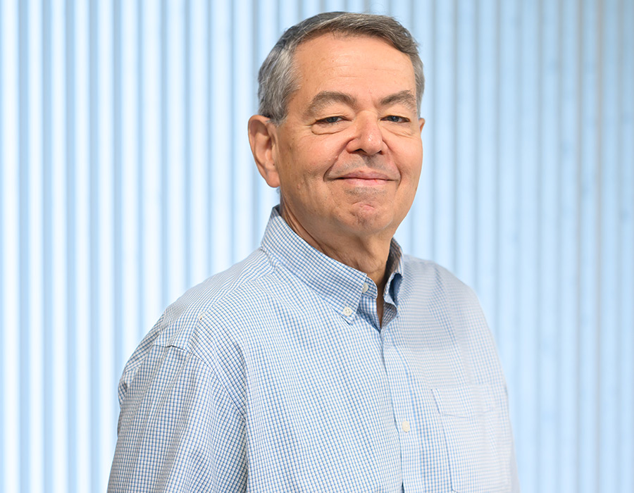 Professor Steve Buchwald smiles in front of a blue background.