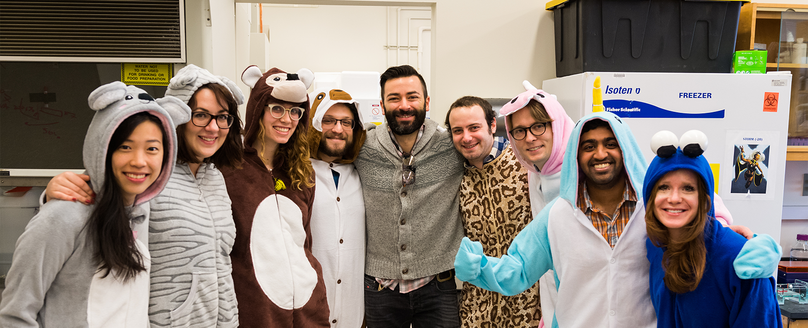 Professor Alex Shalek poses with members of his research group, who are jovially dressed in animal onesies.