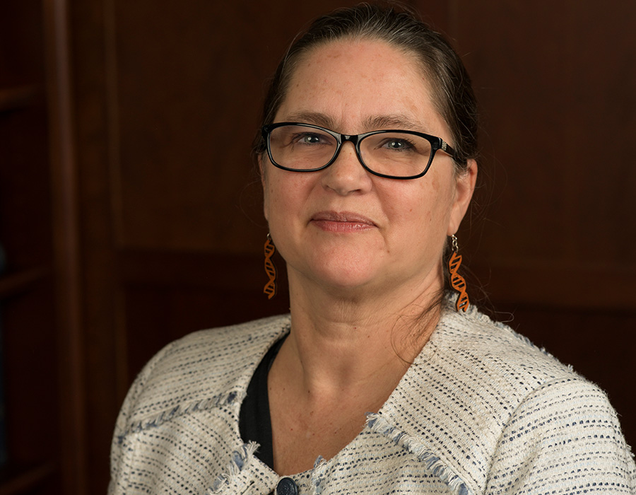 Catherine Drennan smiles in front of a wood paneled wall.