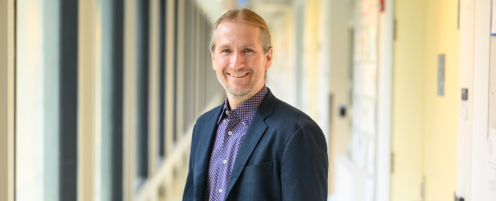 Professor Jeremiah Johnson smiles in a hallway.