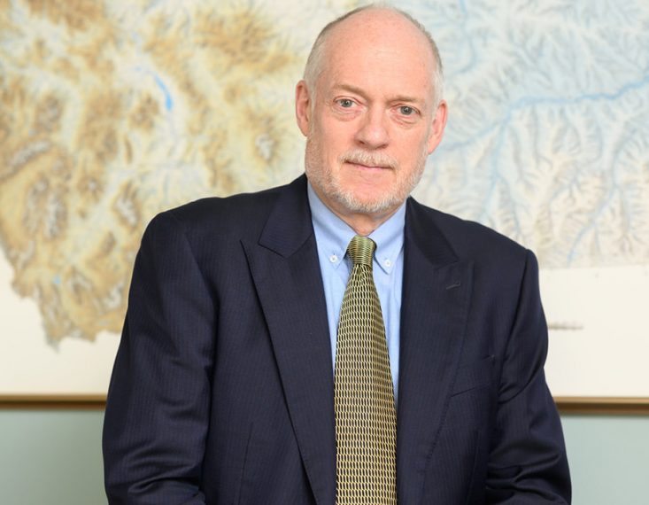 Professor Tim Swager smiles in front of a map.