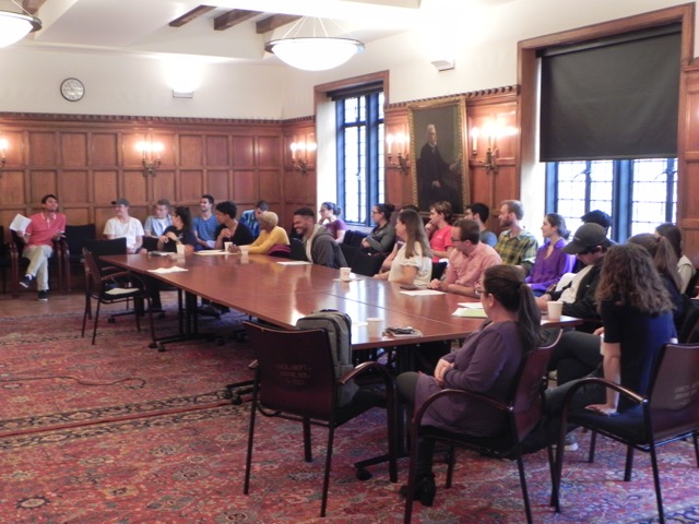 35 people sit in a conference room attending a meeting.