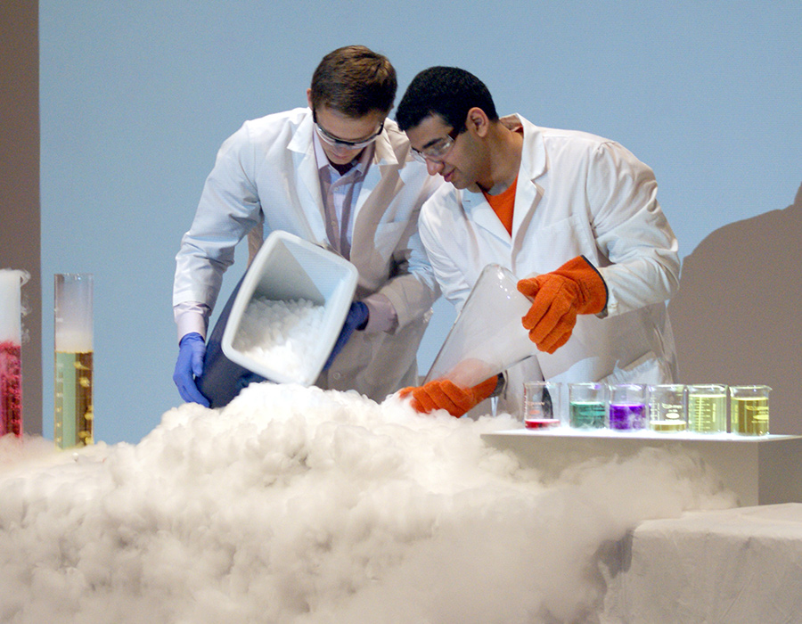 Two undergraduate students demonstrate a dry ice experiment before an audience of schoolchildren.