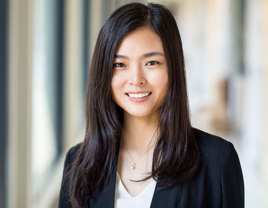 Professor Xiao Wang smiles in a hallway.