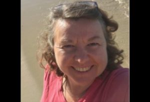 A woman smiles on the beach.