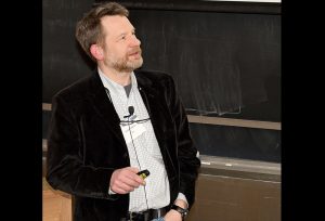 A man teaches a course in front of a chalkboard.