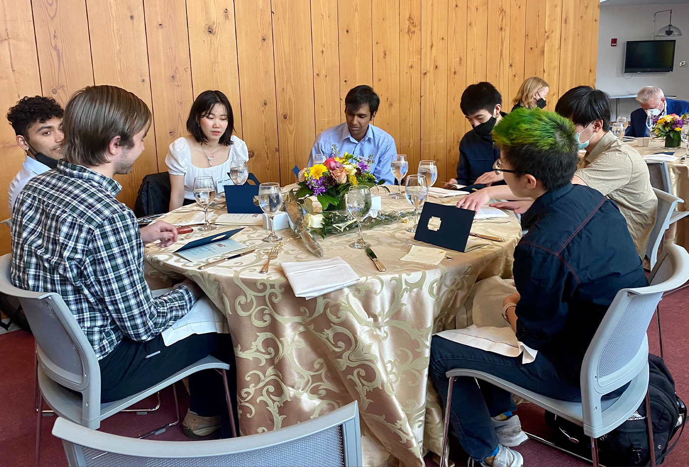 A group of students and faculty sit at a table.