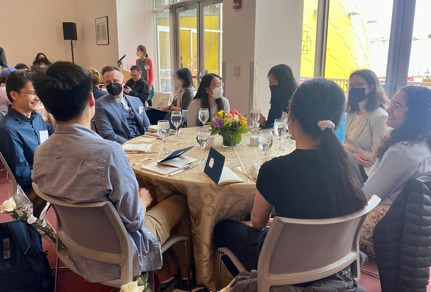 A group of students and faculty sit at a table.