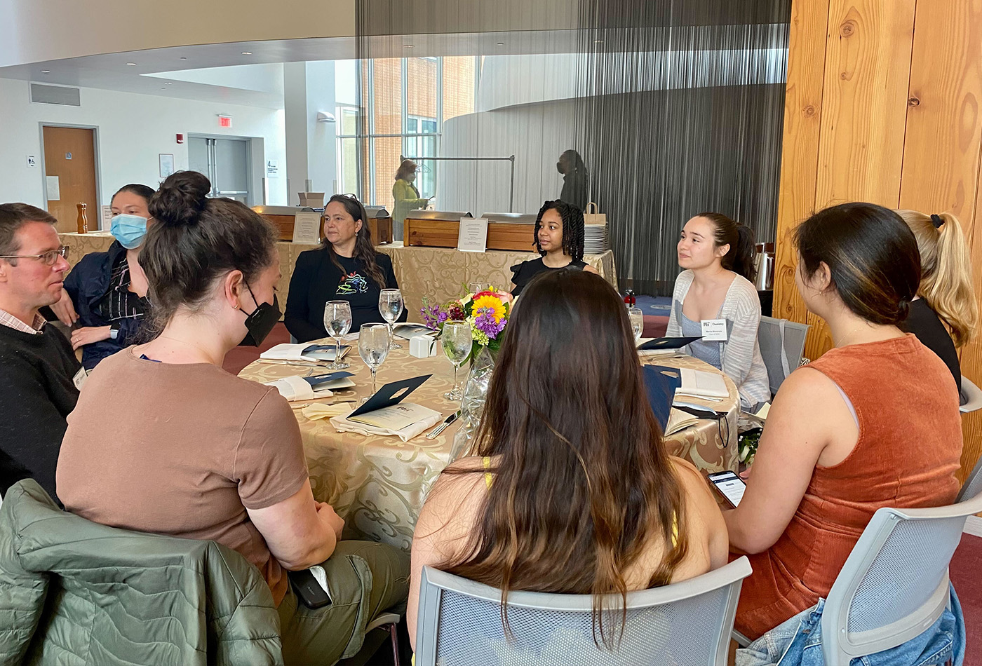 A group of students and faculty sit at a table.