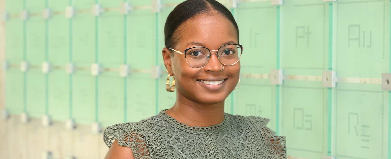 Oleta Johnson smiles in front of a periodic table of elements.