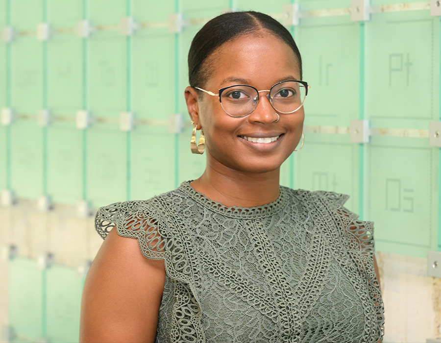 Oleta Johnson smiles in front of a periodic table of elements.