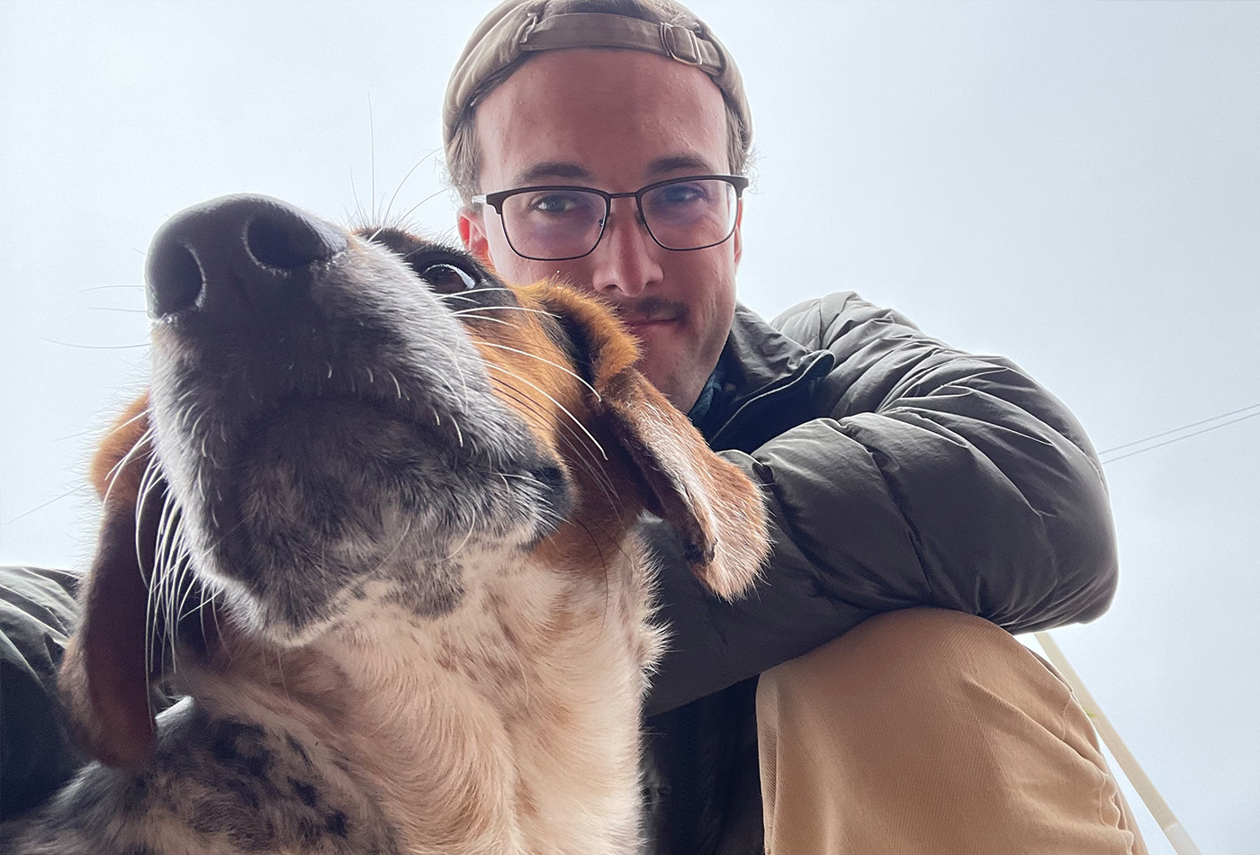 Ashton Davis smiles behind a beagle.