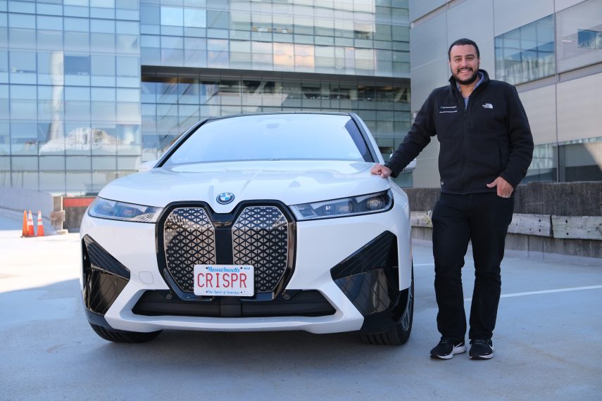 Omar Abudayyeh ’12 stands beside a white BMW whose license plate reads CRISPR.